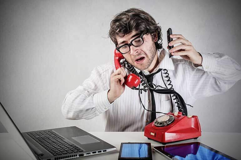 Stressed man holding multiple phones to his ear