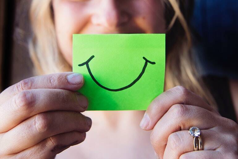 Woman holding green post it with a smile on it