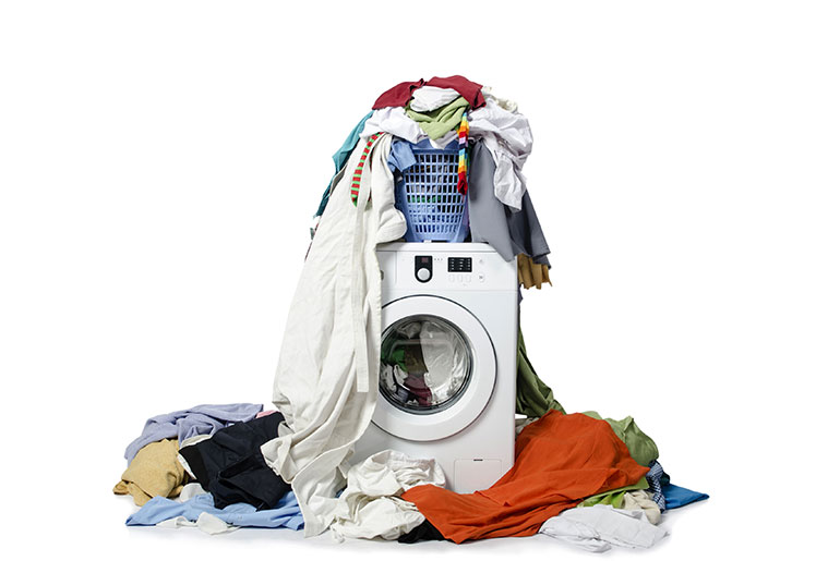 Washing machine surrounded by a pile of dirty laundry