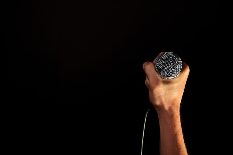 Hand holing microphone on black background