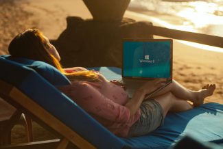 Woman sitting on a beach with a laptop