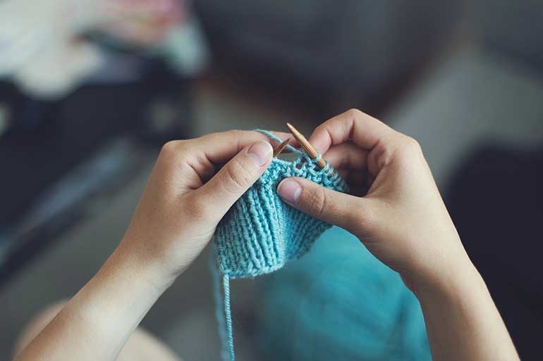 Woman knitting with blue wool