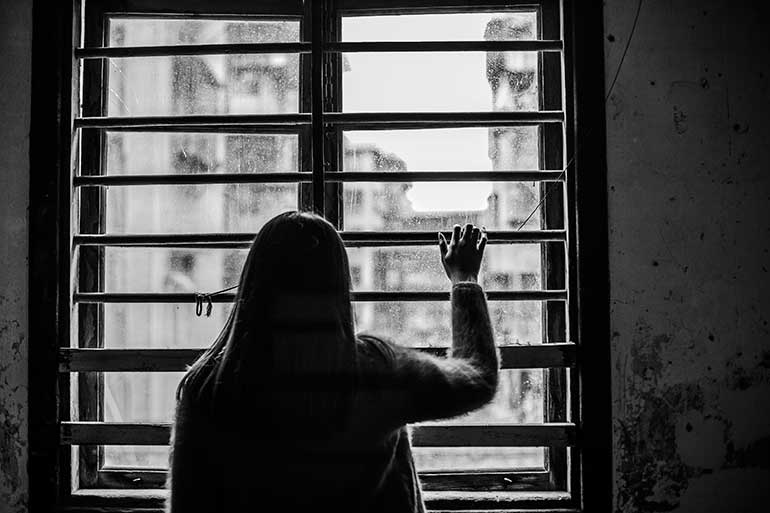 Black and white photo of woman staring out of a window