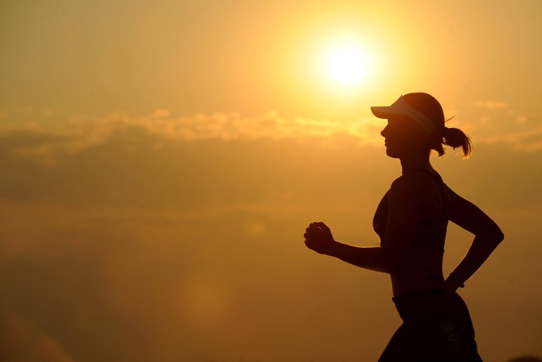 Silhouette of woman jogging against sunset