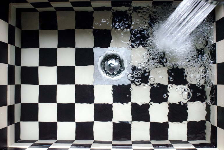 Black and white checked sink with water pouring into it
