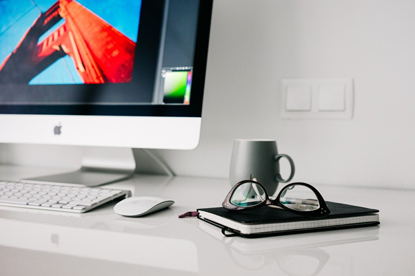 Illustration of notebook and glasses by an iMac