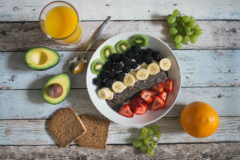 White plate on wooden board with fruit, juice and toast