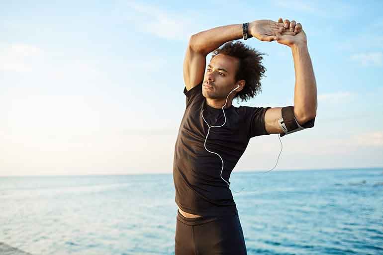 Man in front of the sea stretching
