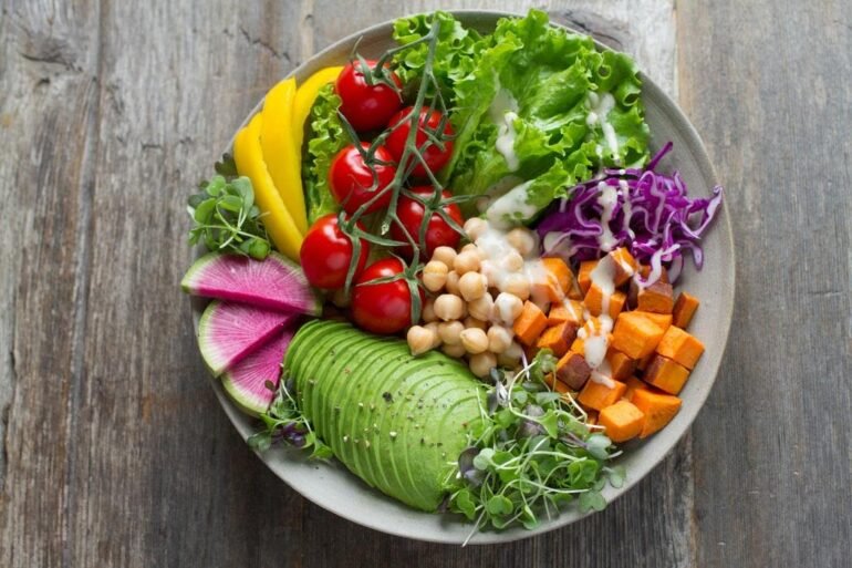 Bowl of rainbow salad on a brown board