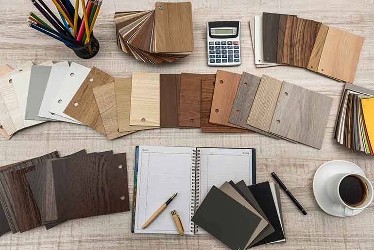 Flooring samples on a desk with calculator and a cup of coffee