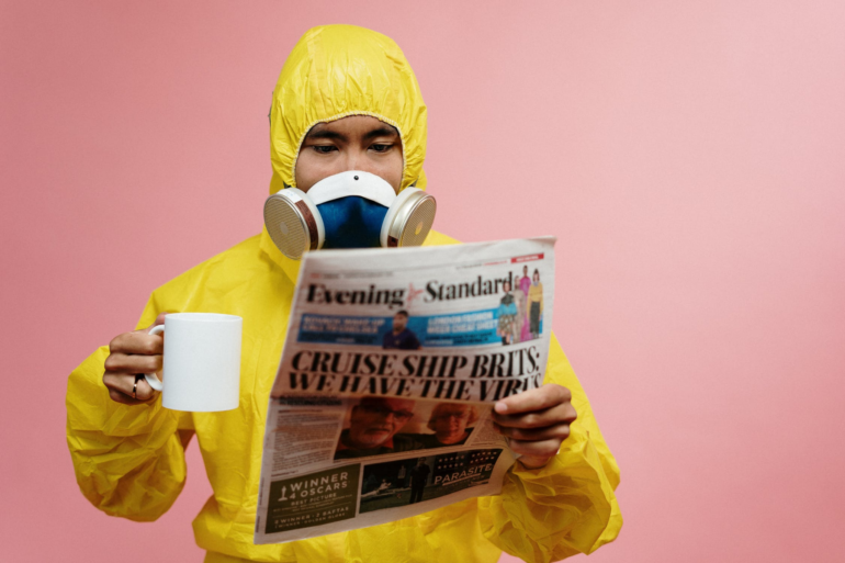 Man in safety gear reading a newspaper and drinking a coffee