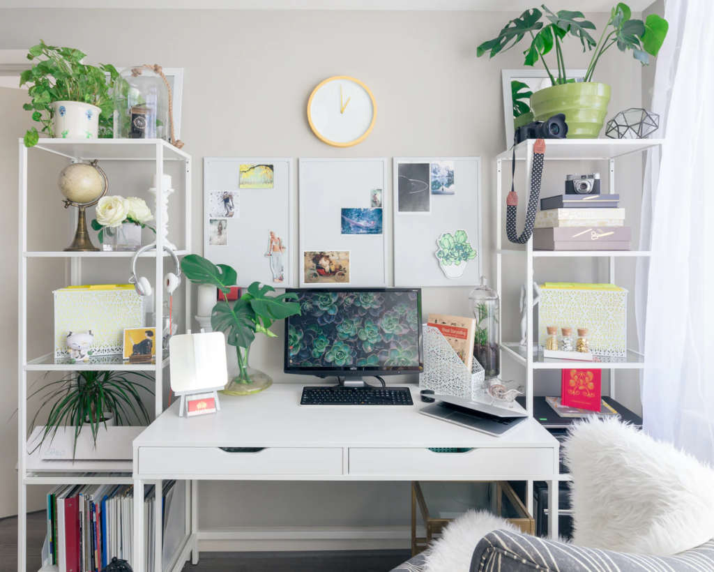Bright white desk surrounded by shelving and plants