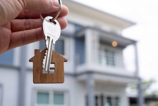 Person holding keys with a house-shaped keyring on it