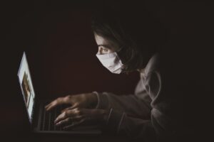Man sat at laptop wearing a face mask