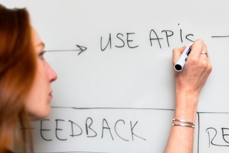 Woman writing "Use APIs" on a whiteboard