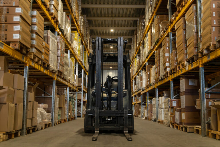 View of high warehouse shelving units with a forklift truck