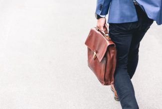 Person in smart clothes carrying a brown briefcase