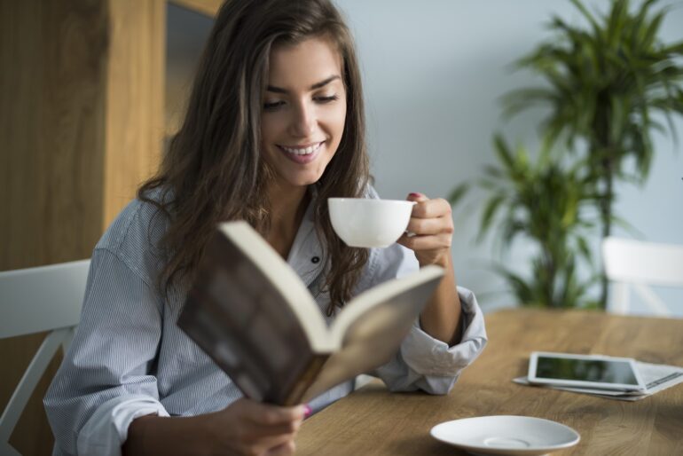 A woman drinking tea while reading a book