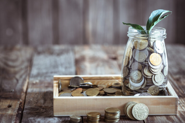 Pile of coins with a plant in a jar