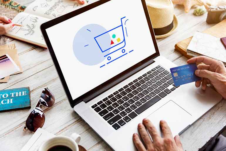 Illustration of a shopping cart on a laptop screen with someone holding a credit card