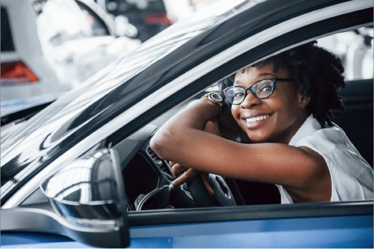 Smiling woman leaning on her car steering wheel
