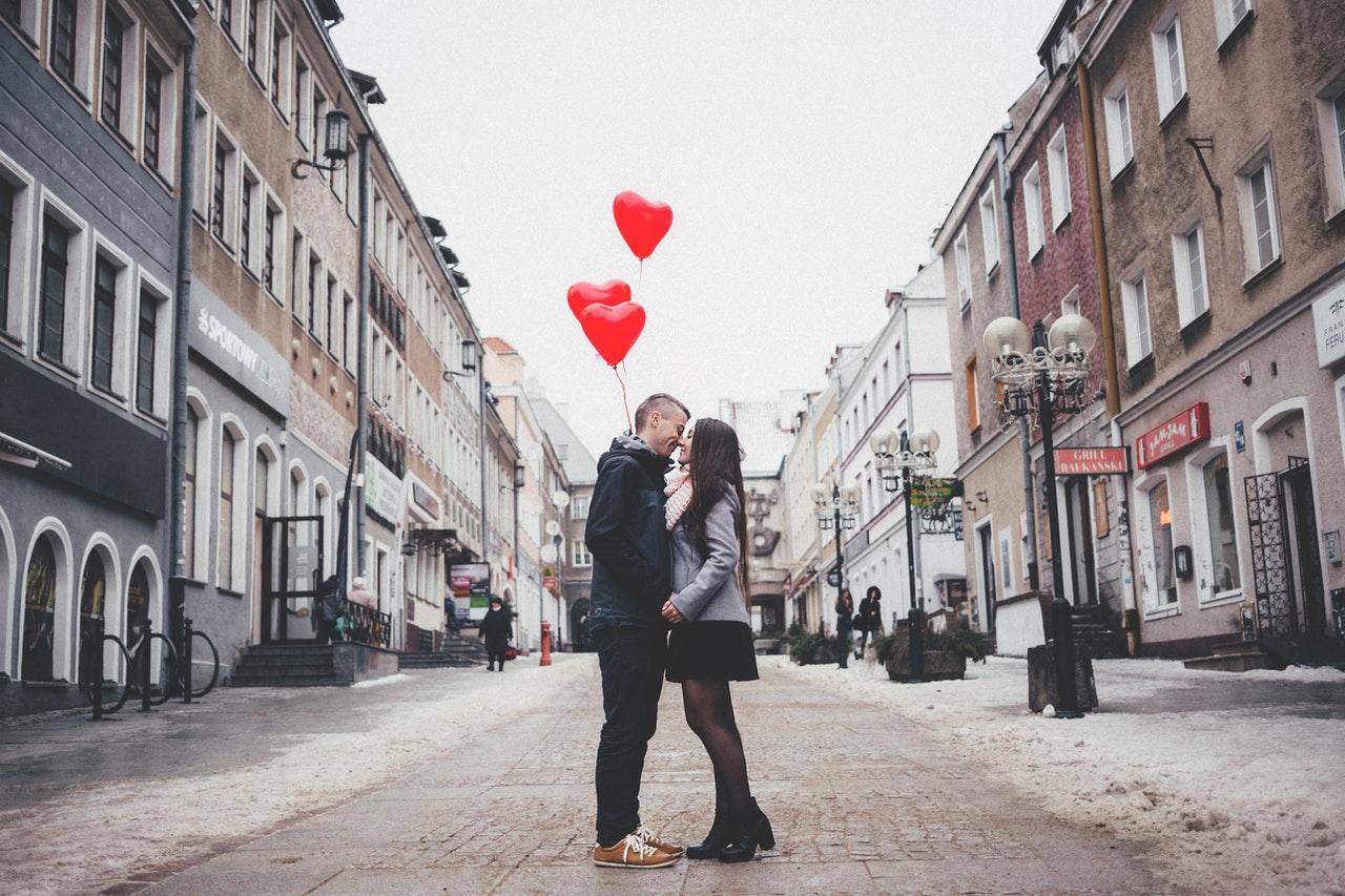 Couple in a street with heart-shaped balloons behind them