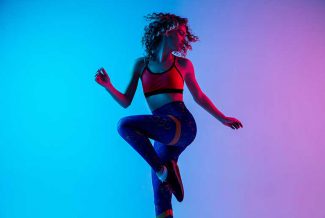 Woman wearing fitness gear and jumping for joy