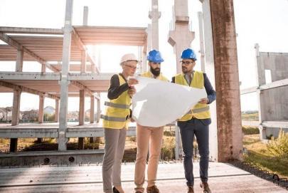 3 Construction workers looking at plans while visiting a site