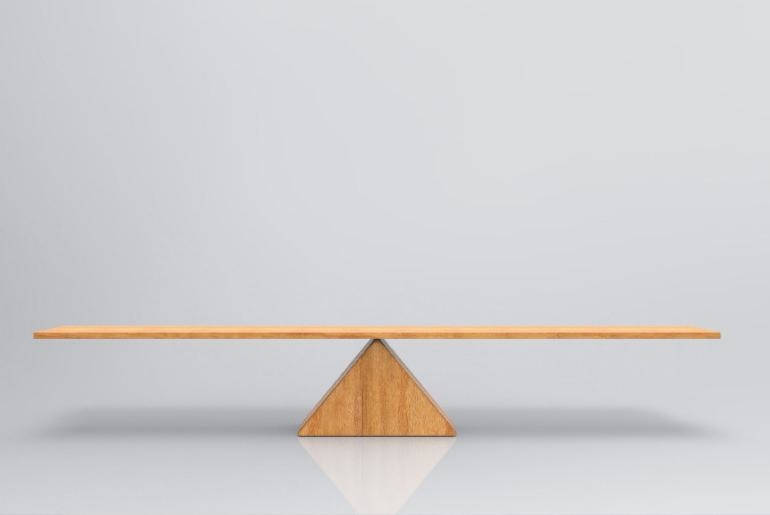A piece of wood balancing on a wooden triangle