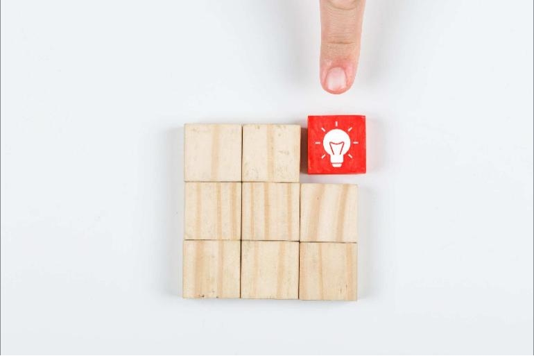 Wooden blocks with one highlighted in red with a lightbulb on it