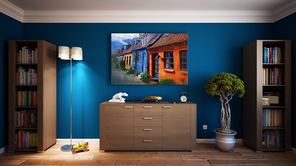 Dark blue walled room with a statement picture of colourful houses hung over drawers
