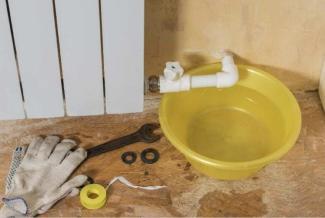 Plumbing tools next to a broken pipe and bucket
