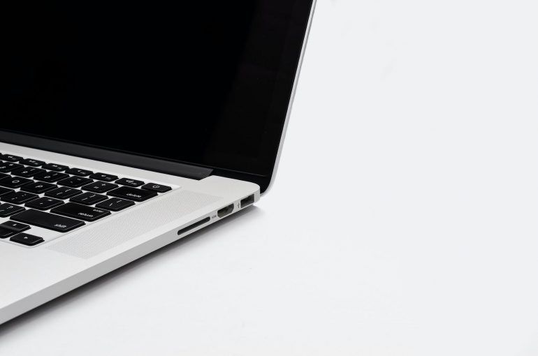 Close-up of a white laptop with black keys on a white desk