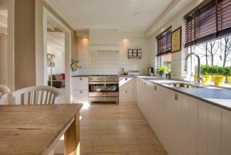 Brightly lit kitchen with white cupboards and a wooden floor