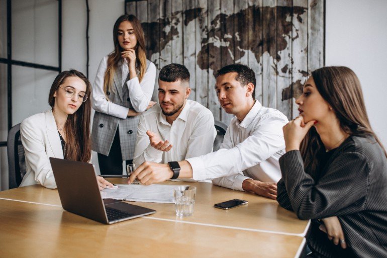 Group of people having a meeting and pointing at a laptop