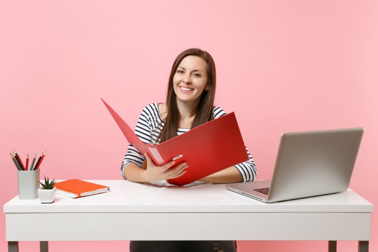 Smiling woman working on project paperwork in a red folder