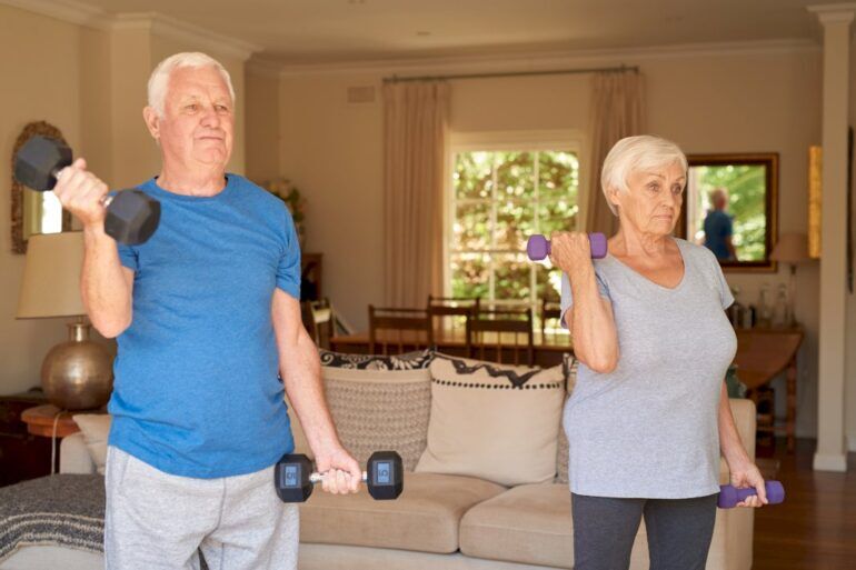 An elderly couple exercising with weights
