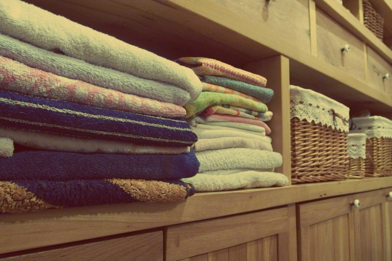 Neatly stacked towels and storage bins above some cupboards
