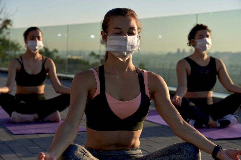 People taking part in yoga while wearing protective fact masks