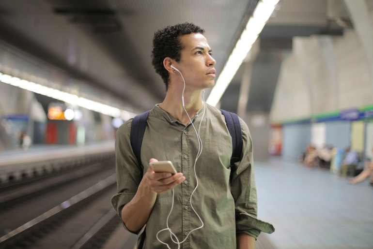 Person listening to headphones while standing in a subway station