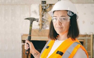 Woman in a hard hat and high-vis vest holding a hammer